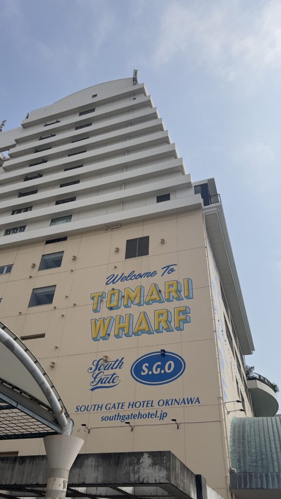 泊港近くのサウスゲートホテル沖縄の外観。壁面にTOMARI WHARFの文字と公式サイトURL。