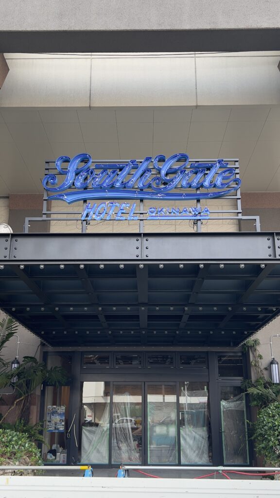 サウスゲートホテル沖縄の1階エントランス。青いネオンサインの看板と工事中の入り口。