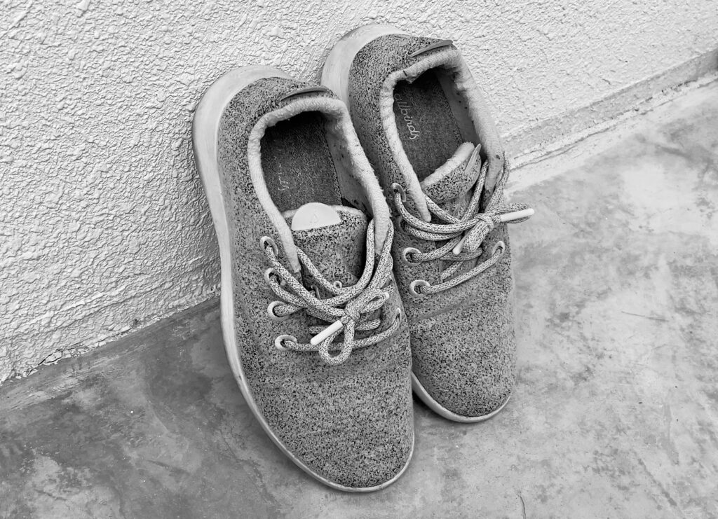 モノクロームで撮影されたAllbirds Wool Runner。壁際に立てかけられ、履き込まれたウールの質感とくたびれ感が、ブランドの歴史と終焉を想起させる。