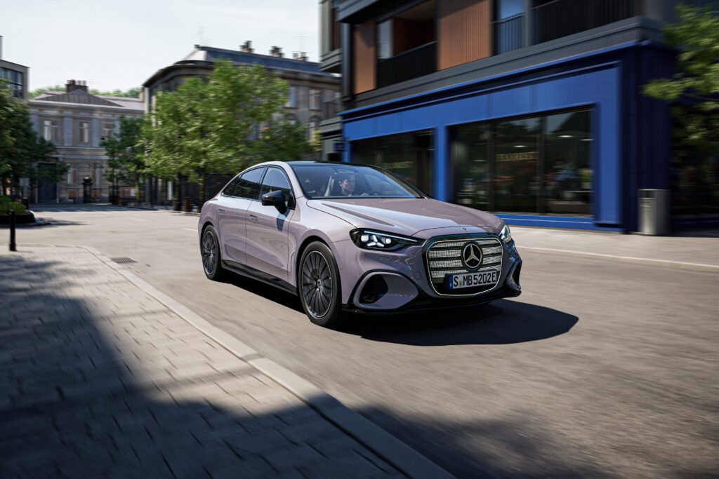 新型電動Cクラス（2026年）市街地走行シーン。モーションブラーで躍動感を表現したフロント3/4ビュー