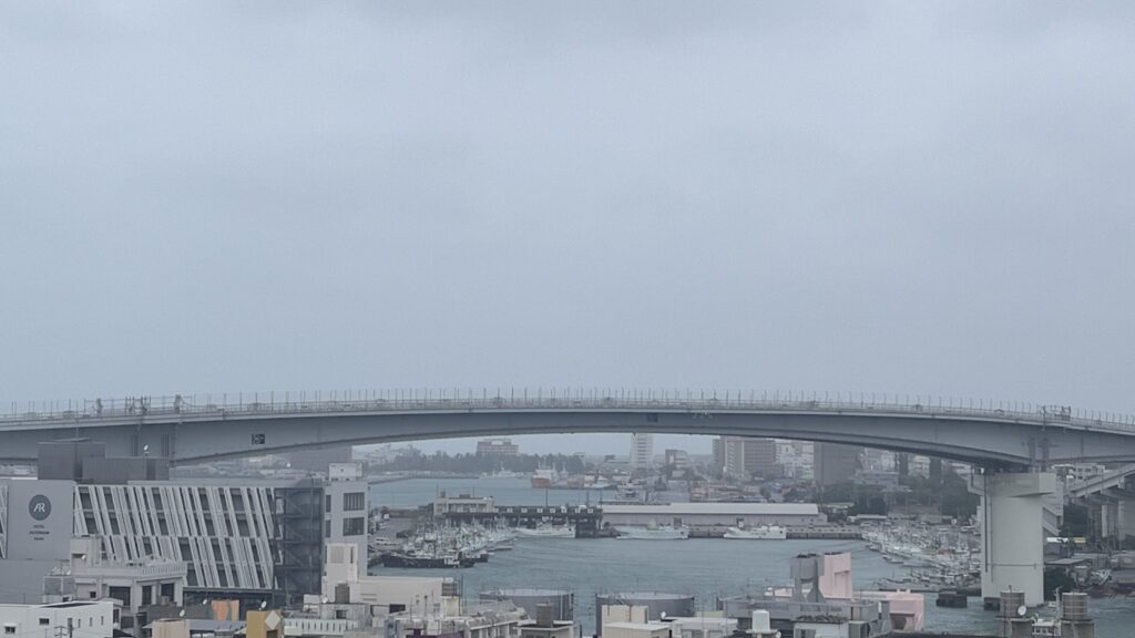 曇天の日に撮影した沖縄・那覇市の泊大橋と那覇港、停泊する漁船の風景