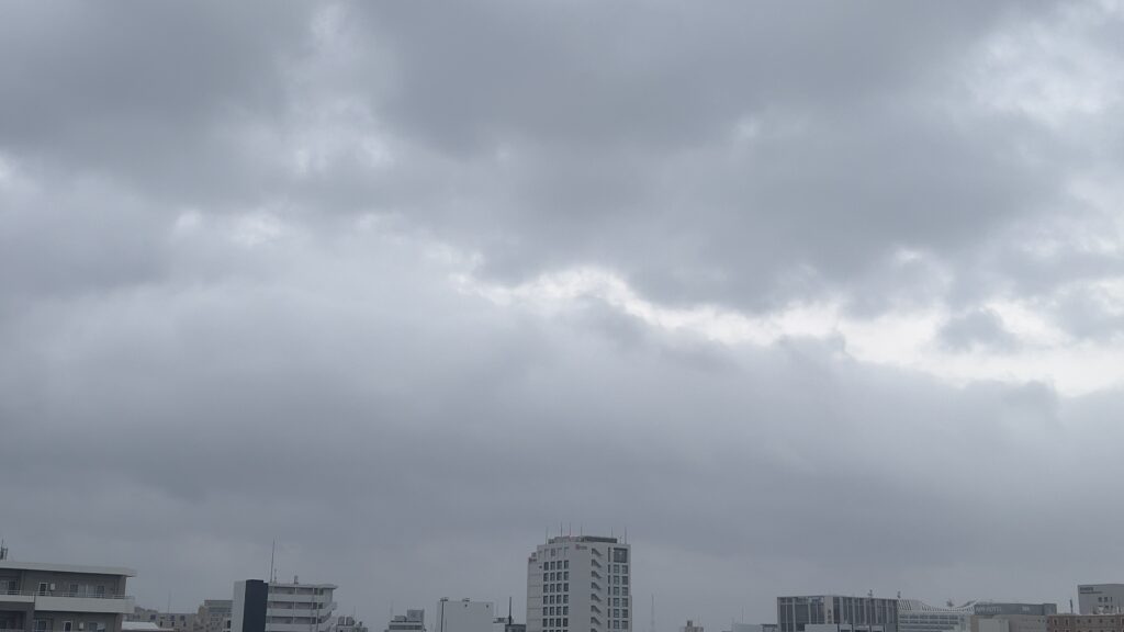 2026年8月26日08時ごろ、那覇市内から撮影した沖縄県庁方面上空の様子。厚い雲に覆われているが、雨風は落ち着いている